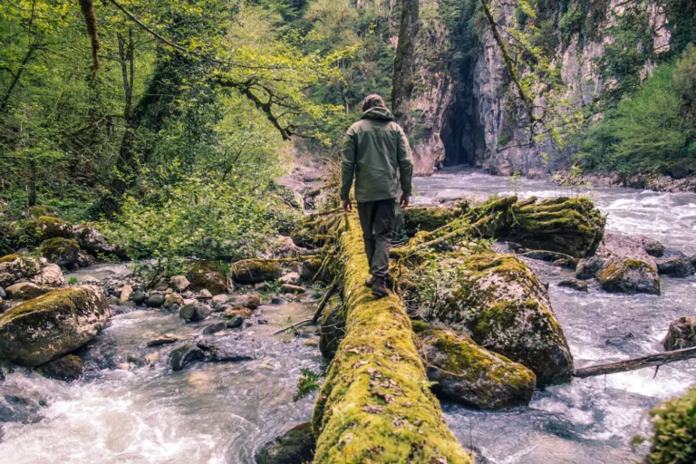 guiding boys. young man walking alone on a log over a swift river