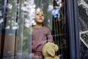 Single parent of a little girl looking out the window hoping her dad will return