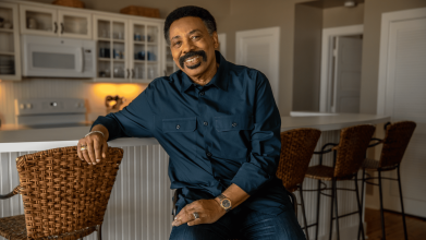 Tony Evans sitting at kitchen island counter, smiling