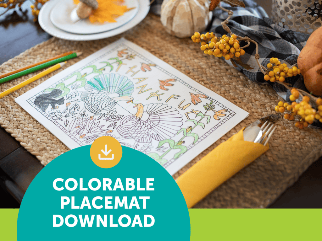 Illustrated placemat on larger woven placemat with wrapped silverware setting, colored pencils and fall table decorations