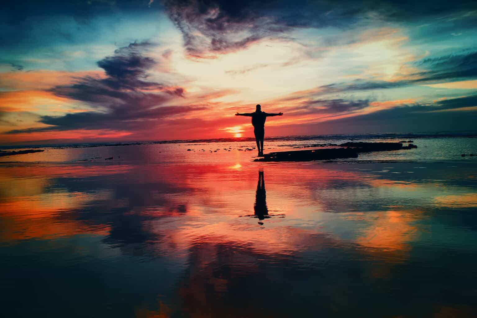 sq man standing on a beach with arms raised
