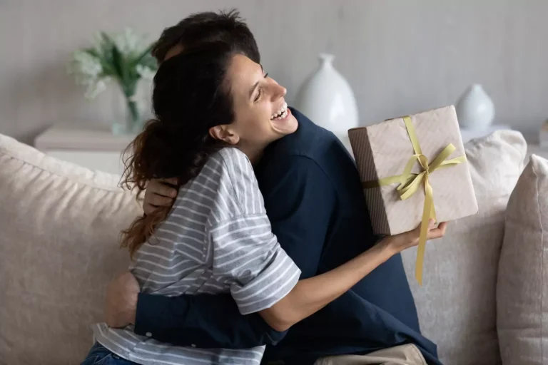 A woman hugs her husband after receiving a gift celebrating a wedding anniversary.