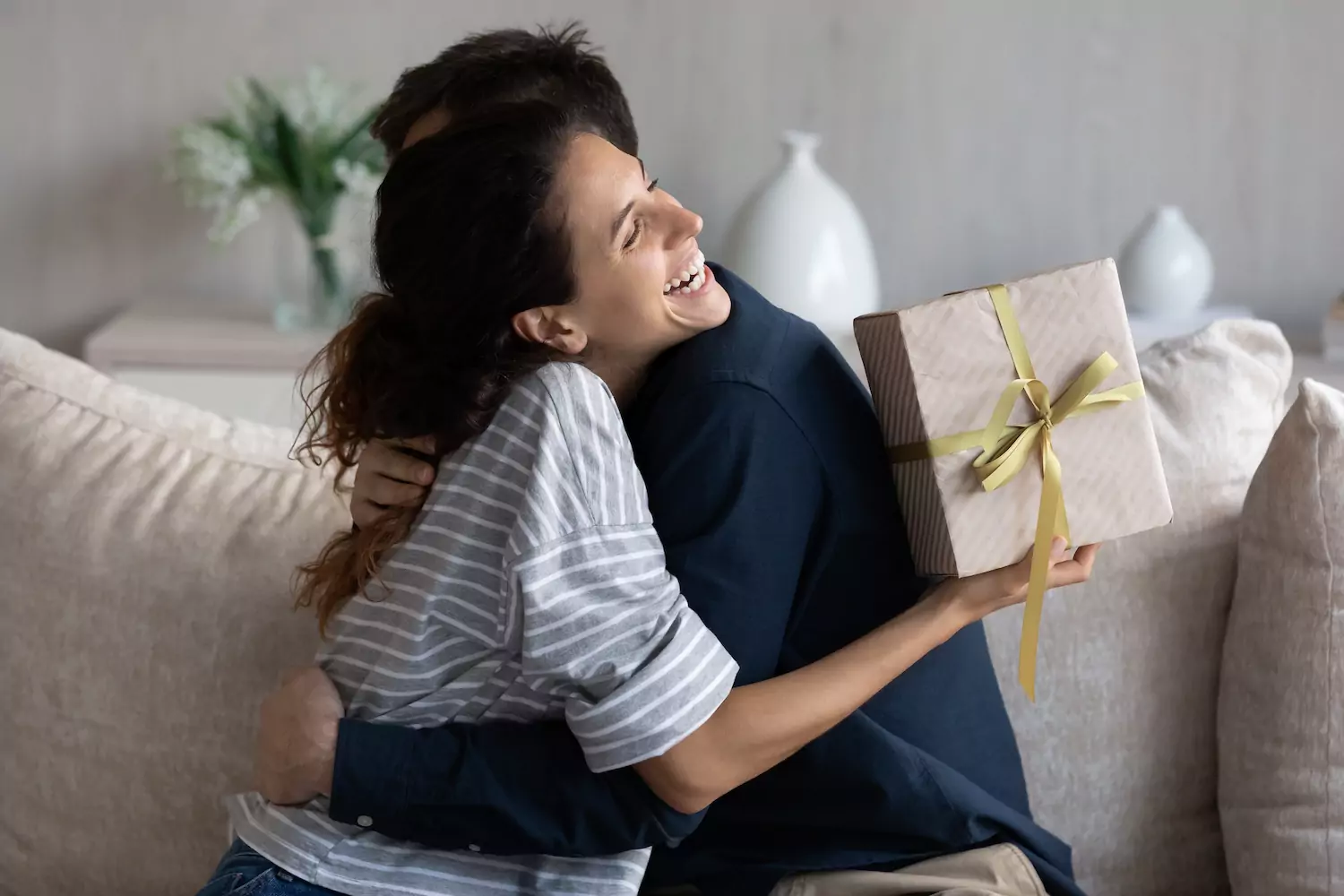 A woman hugs her husband after receiving a gift celebrating an anniversary.