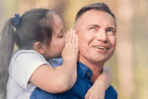 Young daughter whispering into her father's ear