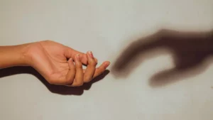 A woman's hand reaches out to the shadow hand of her depression, which has come back for her again.