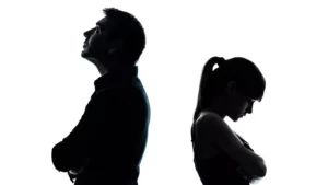 Silhouette of a man and woman standing with their arms crossed, facing away from each other. They have been fighting in marriage and wonder what the Bible says about conflict.