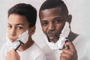 A father and son looking into the mirror together while they shave