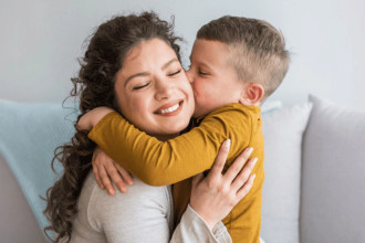 Mom hugging young son as he kisses her cheek