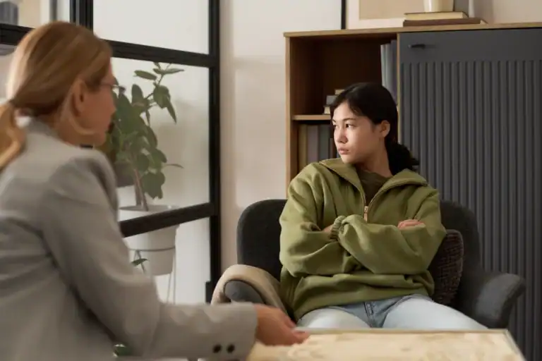 Portrait of angry teenage girl stonewalling therapist during counseling meeting