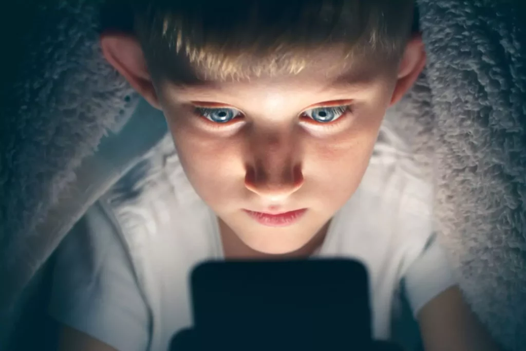 horrors of war are currently at children's fingertips, shown here as a young boy views his phone from under his covers long after he should be sleeping