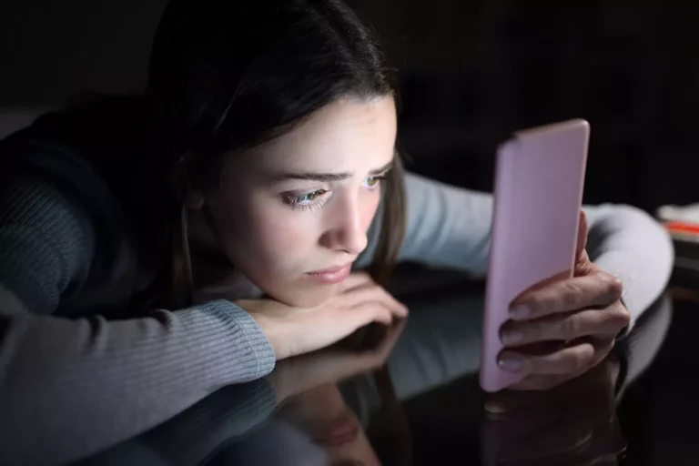 A social contagion like rapid onset gender dysphoria can affect teenaged girls like this dark haired teenager sadly looking at her phone late at night on her bed