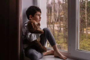 boys emotions. sad young boy sitting in a window