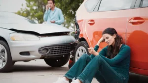 Photo of a woman sitting next to a fender bender wondering how shoe could understand the other driver when he miscommunicated, causing the crash.