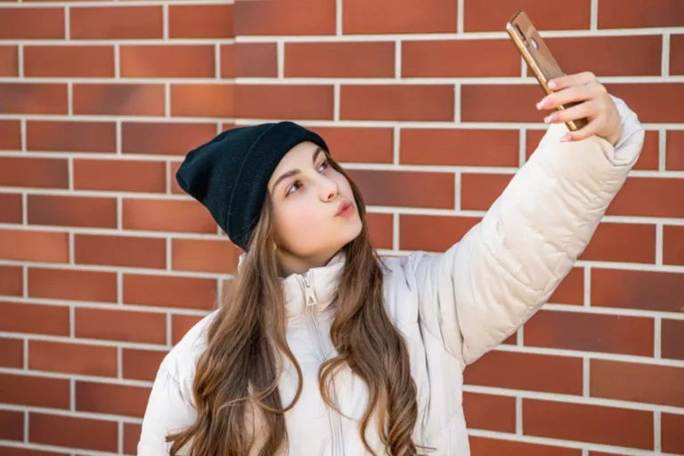 Teen with a smartphone taking a selfie, provoking the question
