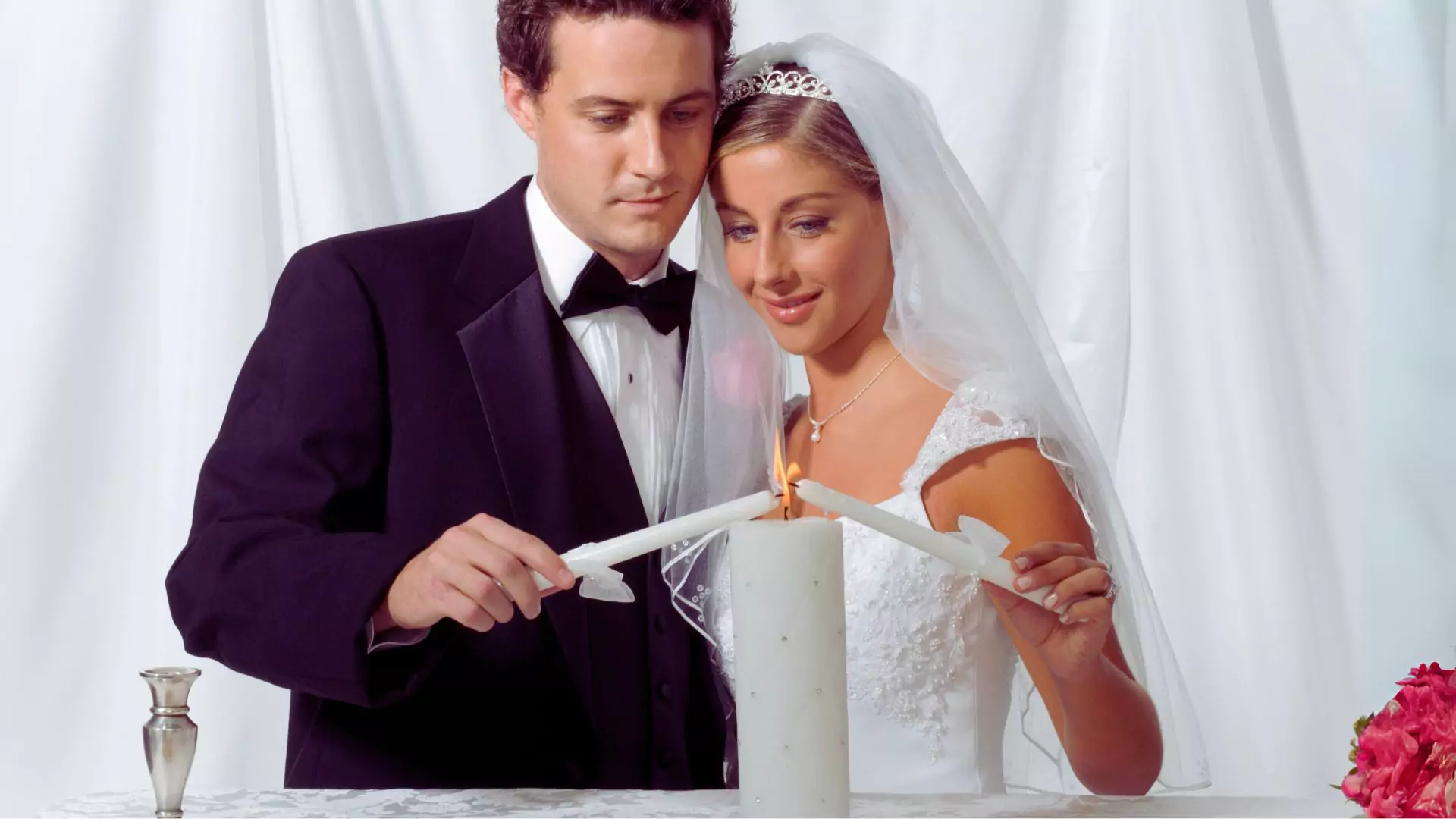 Photo of a man and woman lighting their unity candle during their marriage ceremony.