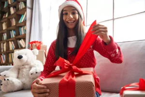 teen girl sitting on a couch opening a Christmas present