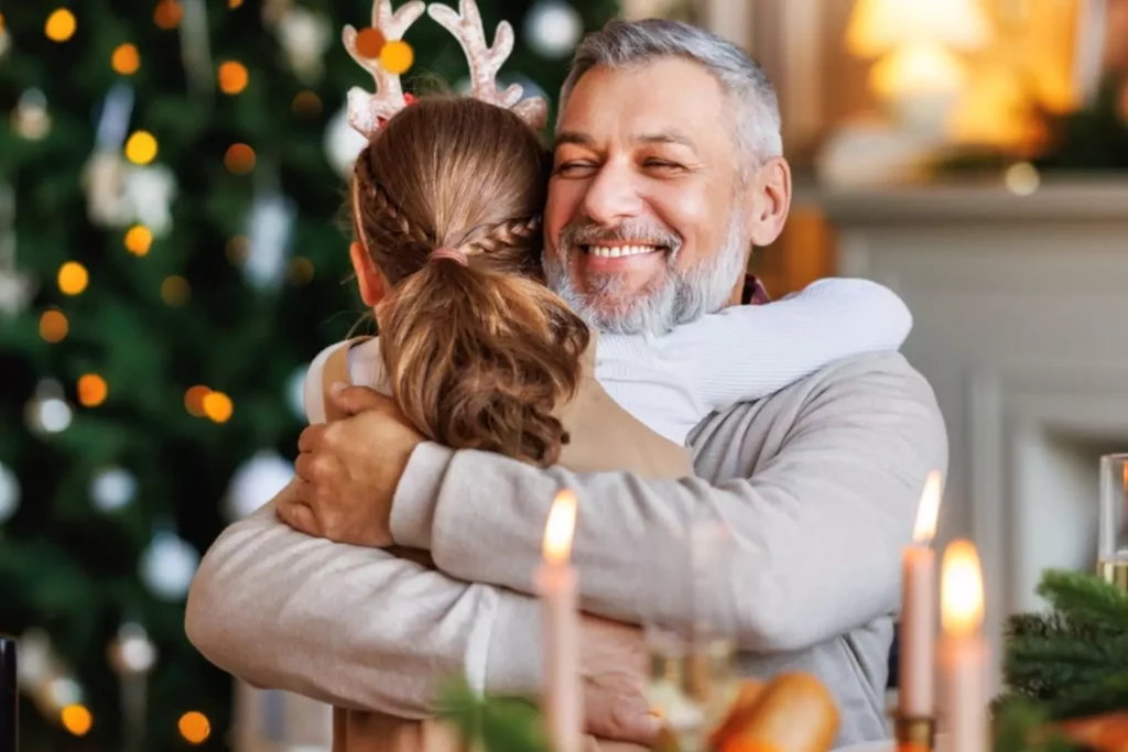 gift ideas for adult children-grandfather hugging his granddaughter at Christmas