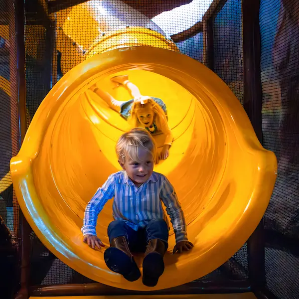 A boy and his sister at the end of a tube slide