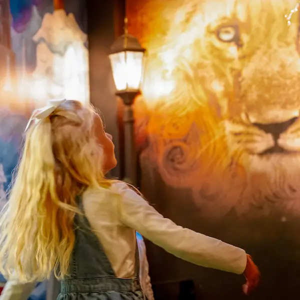 Girl looking at a mural of the lion Aslan from Narnia
