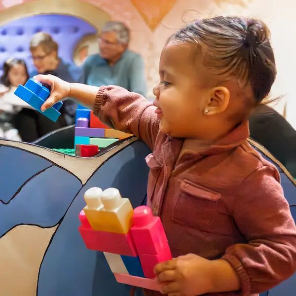 A toddler playing happily with large blocks