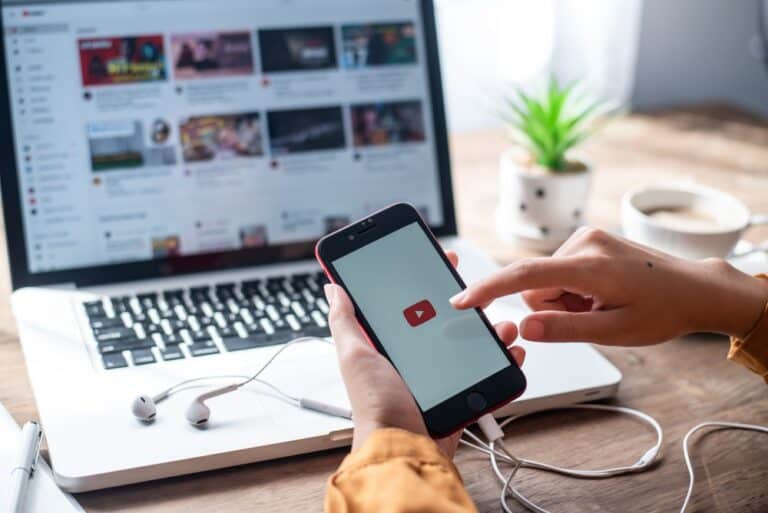 Stock photo of someone looking at YouTube on their phone and laptop