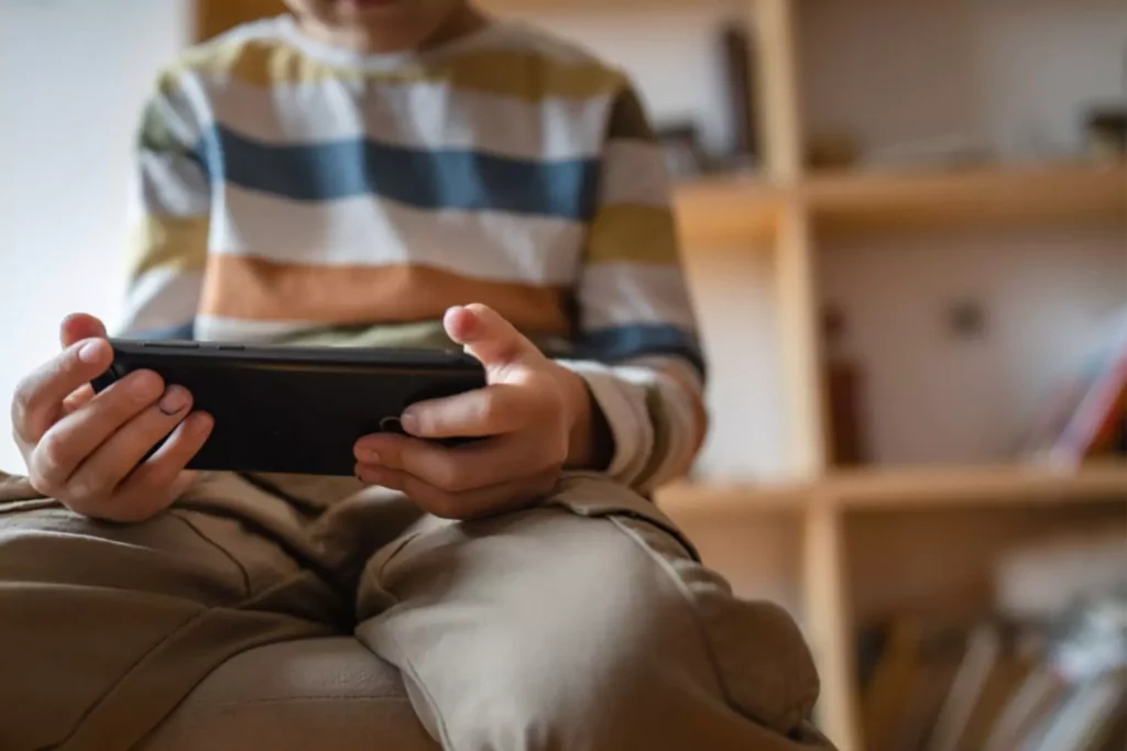 young boy alone in his room looking at his phone screen