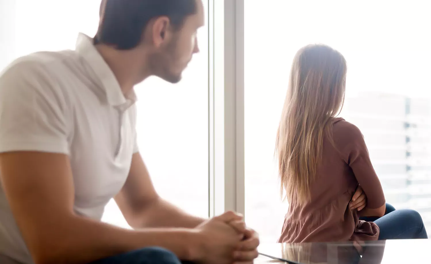 A photo of a man looking apologetically at a woman, whose back is turned. He is longing for forgiveness.