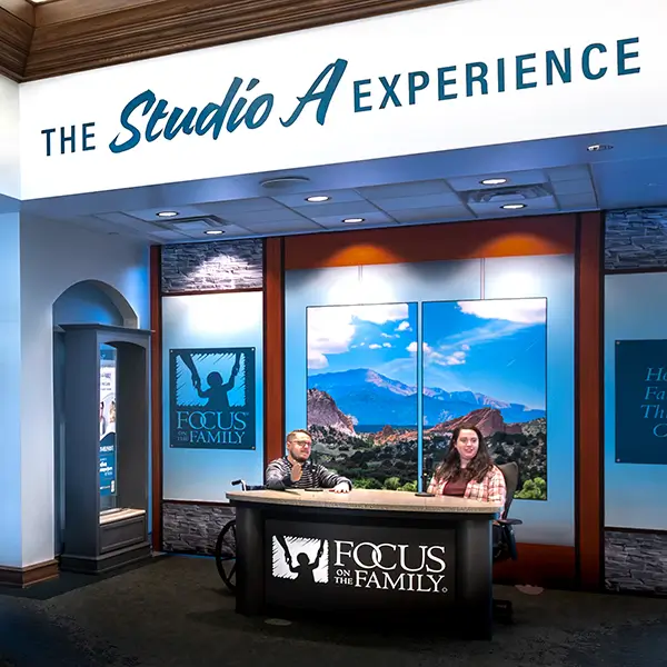 Two people sitting behind a radio broadcast desk at the Focus on the Family Welcome Center