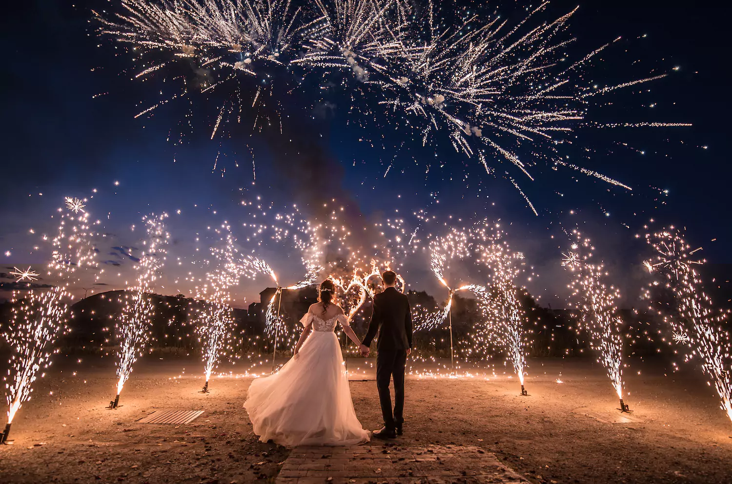 A couple who were just married stand amidst fireworks on their wedding night.