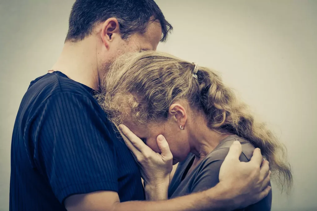 A man hugs his grief-stricken wife. Telling the whole truth offers hope and freedom from pron addiction.