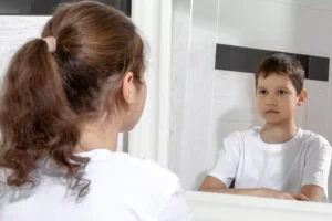 Girl in looking in the mirror and seeing the image of a boy. a child wants to be the opposite sex