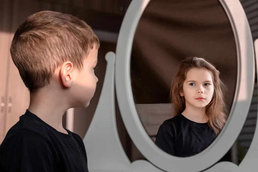 Gender identity issues. Boy looking into a mirror and seeing himself as a girl.