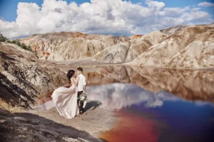 A young bride and groom stand in a beautiful, mountainous landscape at the edge of a lake. Watch out for these unrealistic expectations in marriage.