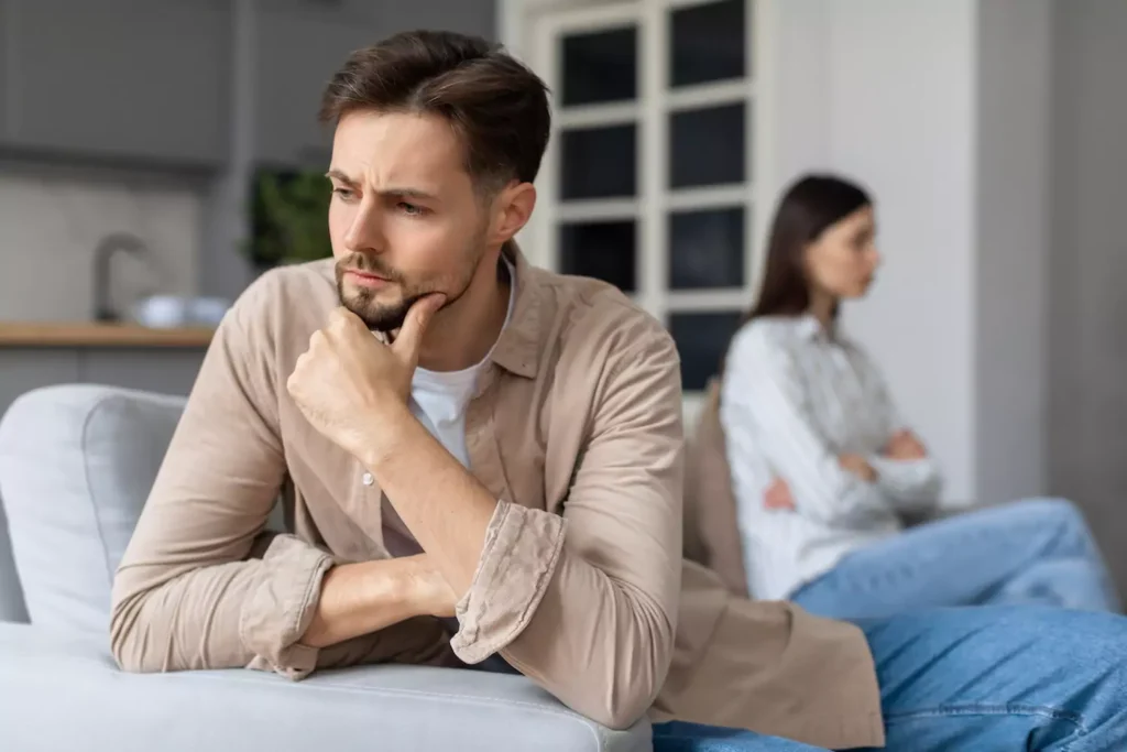 A man and a woman sit on opposite ends of a couch, turned away from each other. Here's how to identify and deal with a spouse on the autism spectrum, and to navigate autism and marriage.