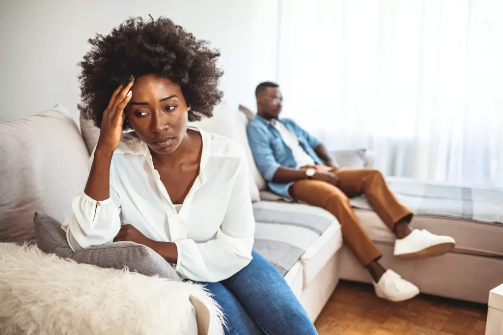 A woman sits on a couch on the other end from her husband, with whom she is clearly angry. Imagine they hit one of your “buttons,” and you had an angry outburst at your spouse. How do you repair the relationship?