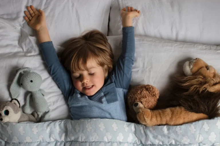 little boy tucked in bed with four stuffed animals for a bedtime routine that works