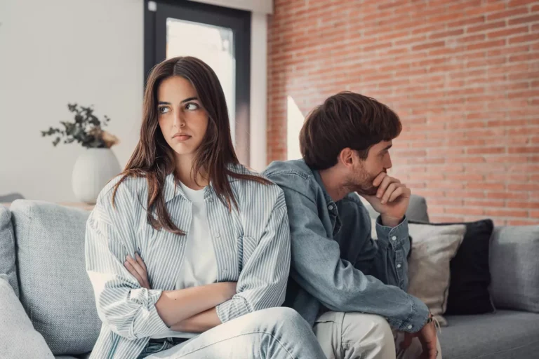 A woman sits on the couch with here back turned to her husband, arms crossed in front of her chest with an annoyed look on her face. Her husband sits with his back turned to her with his chin on his hands as if frustrated. After being married for a while, your spouse’s patterns can turn from cute quirks to annoying habits. Knowing how to cope is important.