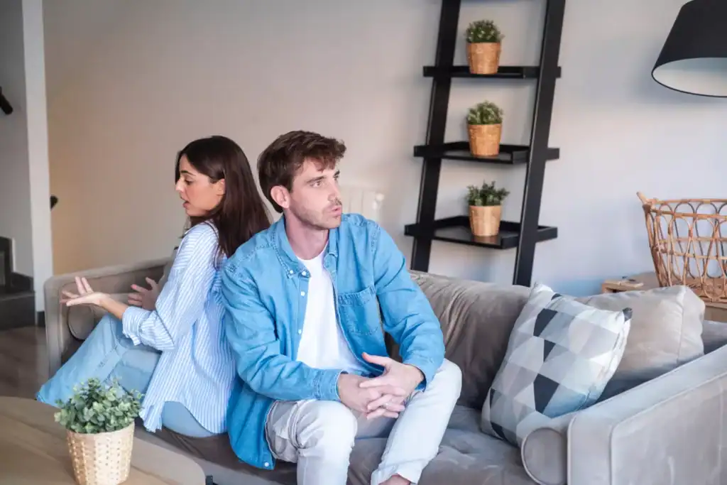 A woman who married an introvert, sitting back to back with her husband trying to talk to him while he clearly wants to be elsewhere.