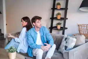 A woman who married an introvert, sitting back to back with her husband trying to talk to him while he clearly wants to be elsewhere.