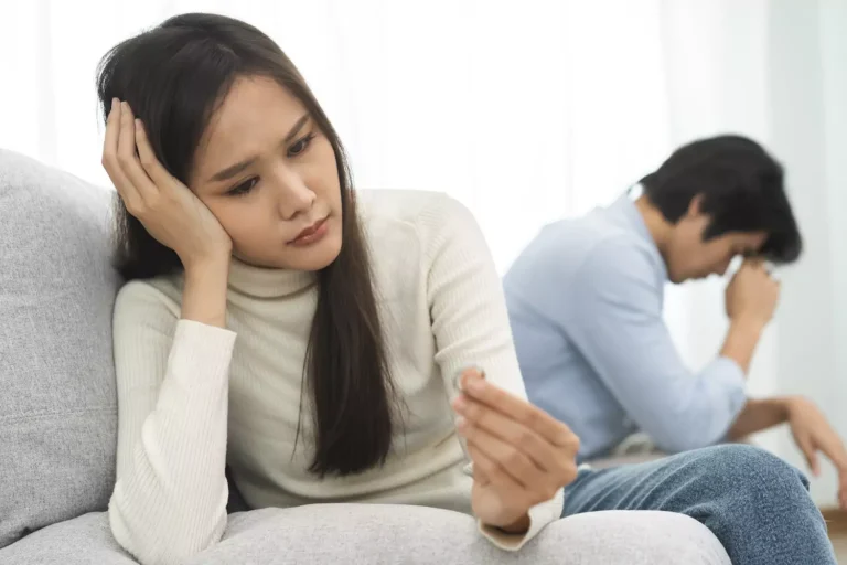 A woman looks at her wedding ring on one end of a couch, while a man holds his head dejected on the other end of the couch. Should you tell your wife about infidelity? Is it better to be honest and hurt your spouse and risk your marriage?