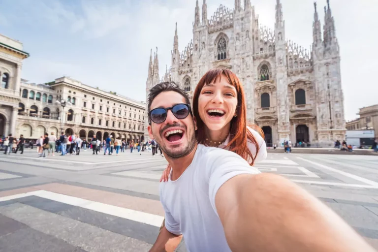 A young couple laughs together as they take a selfie in front of the Milan Cathedral. A simple way to keep your marriage fresh and fun — take every opportunity to share laughter-filled moments with your spouse.