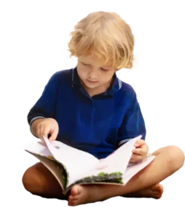 A young child sitting cross-legged and looking at a book
