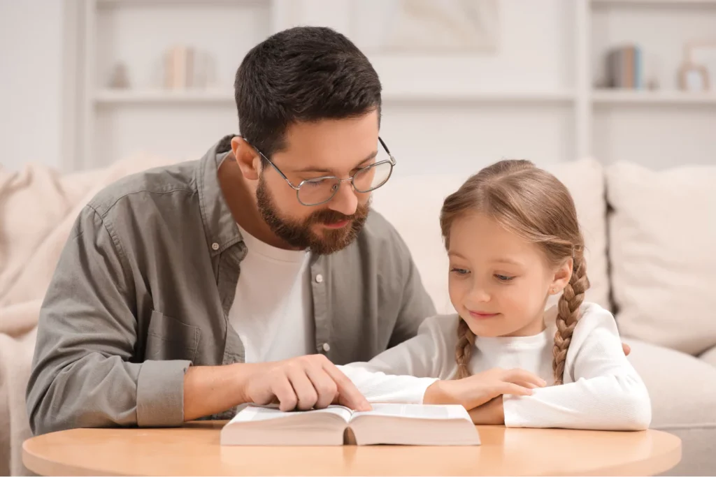 Father teaching child about God from the Bible, leading her to Christ