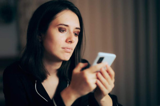 A sad woman looking at her phone