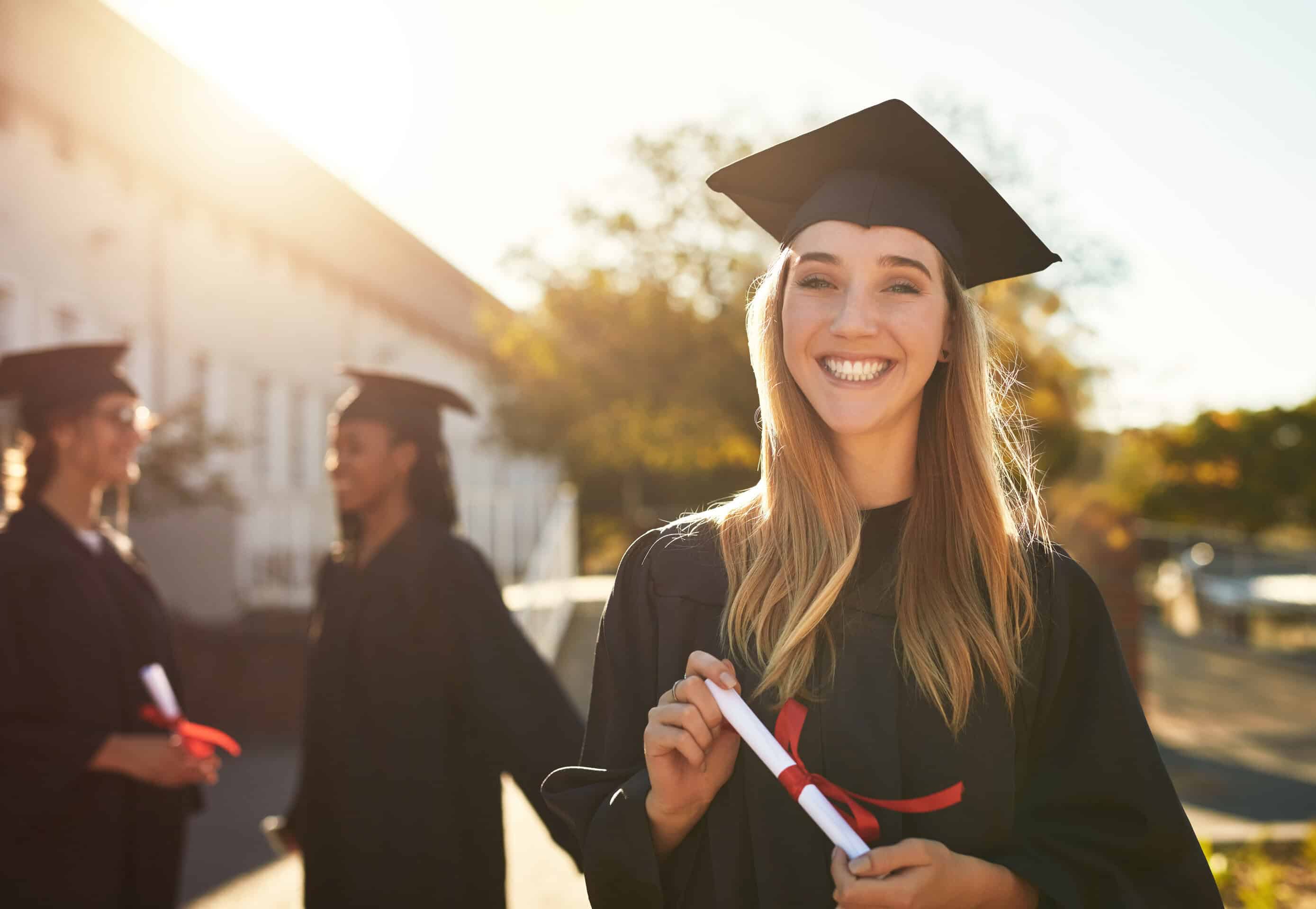 Portrait of a happy young woman holding a diploma on graduation day.