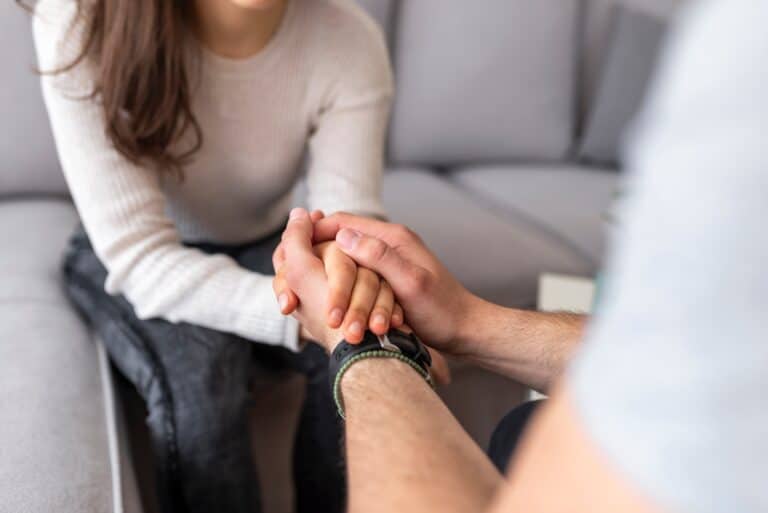 Close up of a couple holding hands and forgiving spouses.