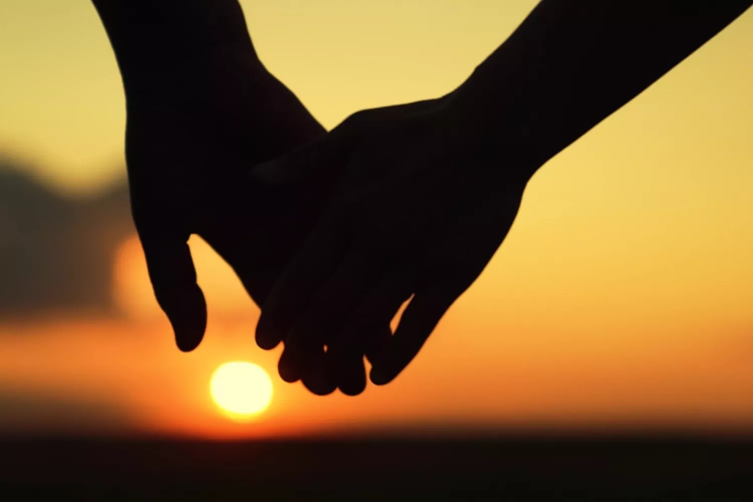 Silhouetted couple holding hands at sunset, symbolizing the love and faithfulness seen in the story of Ruth and Boaz.