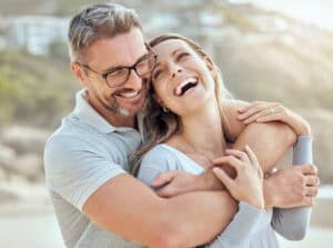 A middle-aged couple hugging and laughing.