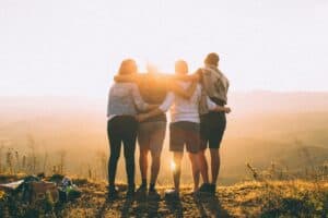 This image shows four friends standing together with their arms around each other. What Does the Bible Say About Friendship?
