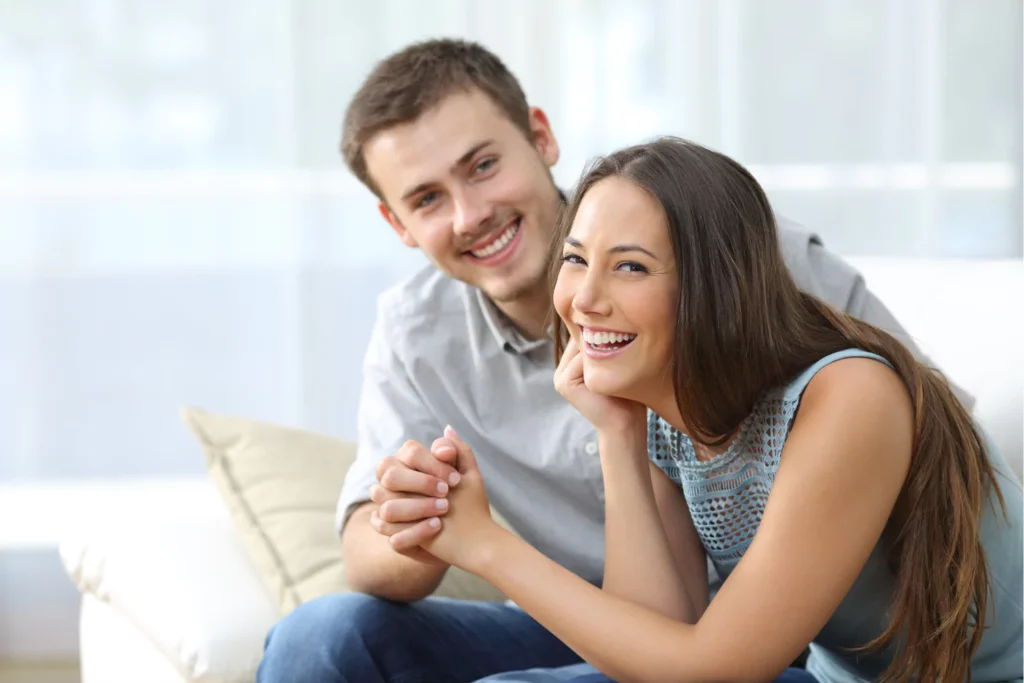 Smiling wife holding hands with her husband while sitting together, showing support for husband’s calling